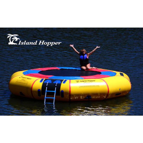 Island Hopper 15' Classic Water Trampoline in the lake with a girl sitting on the edge of the inflatable water trampoline with her hands up.
