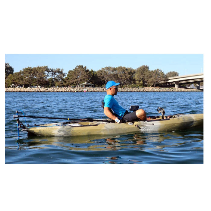 Bixpy Pole Steering system attached to a kayak and in use out on the water. Steered by a man in blue hat and t shirt and lack shorts. The kayak is pea green with white and grey to blend as camouflage.