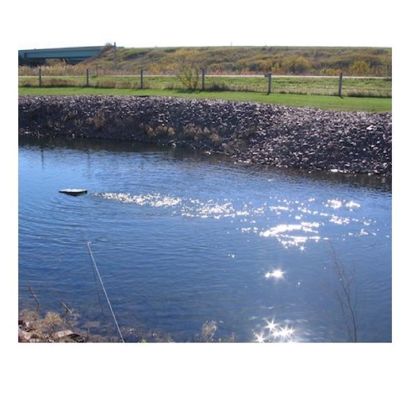 A Kasco De Icer Horizontal Float is in use in a pond and you can see the ripples in the water from the circulation.