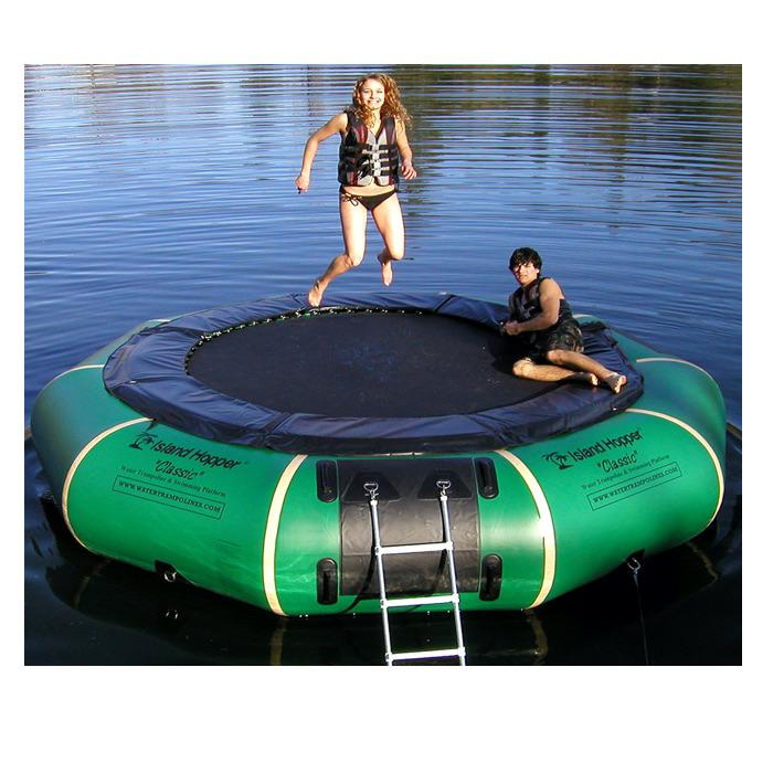 Girl jumping on the Island Hopper 15' Classic Water Trampoline on a white background.  Yellow inner tube, black trampoline surface, red and blue trim. 