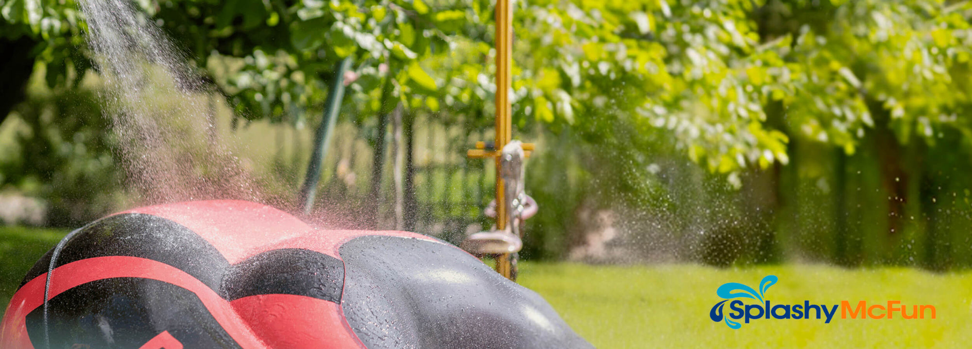 A Step-By-Step Inflatable Boat Care Routine. A red and black inflatable boat is shown being washed down by a hose. It is a closeup of the boat and we see green grass and trees in the background.