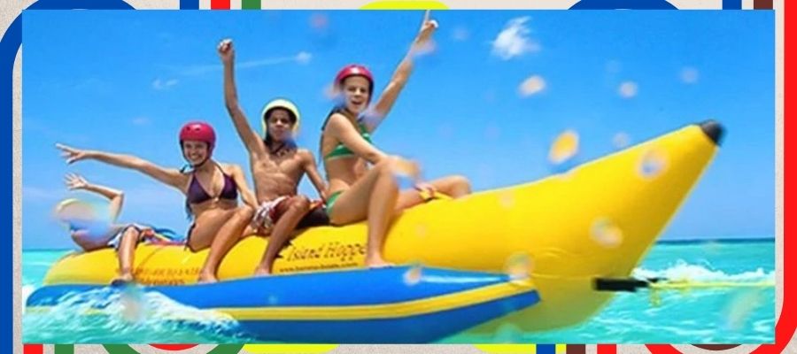 Banana Boat Tubes Bring Big Fun on the Water! 4 teenagers ride on a yellow banana boat tube on clear blue ocean water.