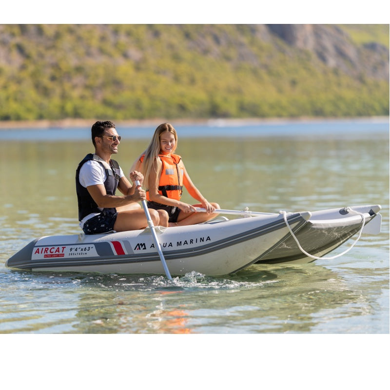 Two people on an inflatable boat with Aircat branding on a lake.