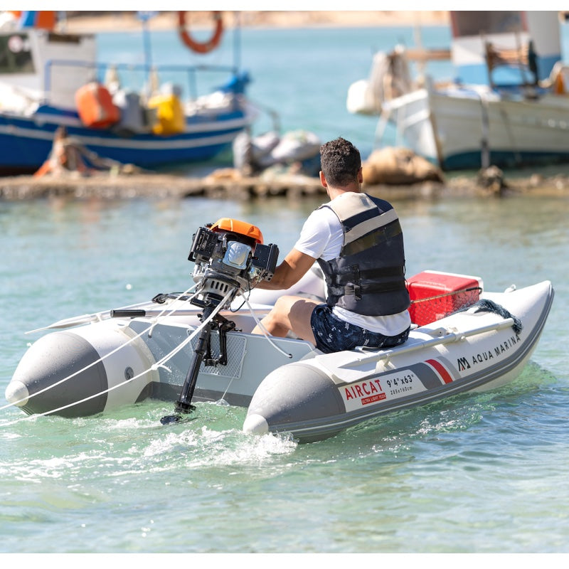 Person on an inflatable boat with a motor, surrounded by water and boats in the background