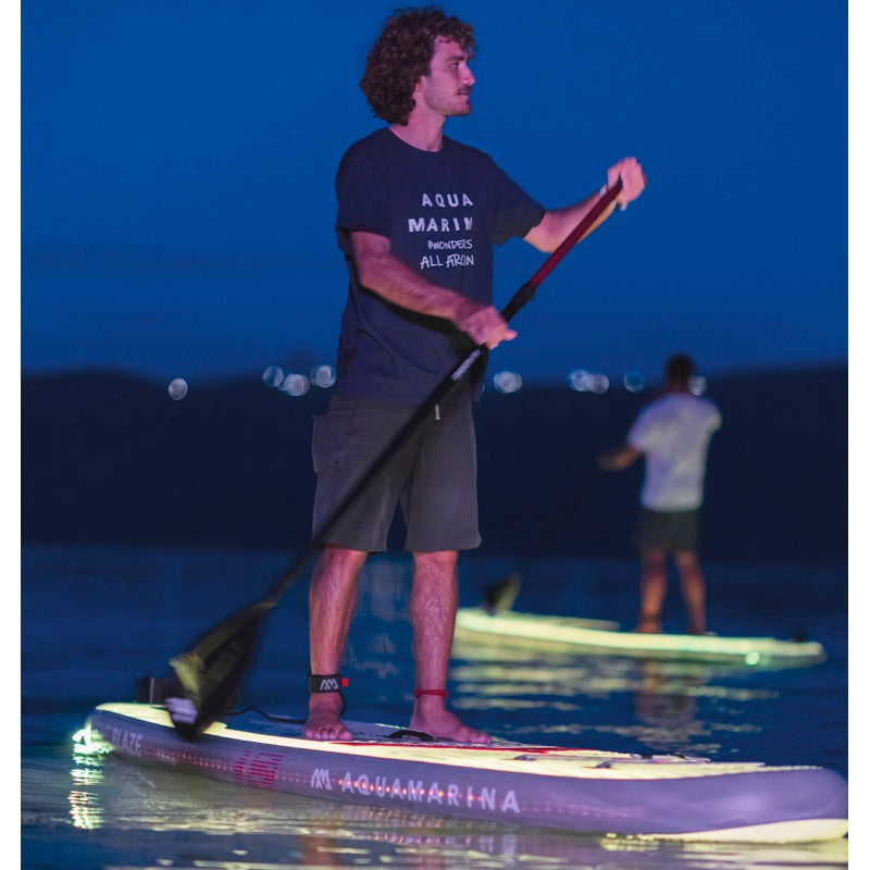 A person paddleboarding at night with an illuminated Aqua Marina Blaze Sup. 