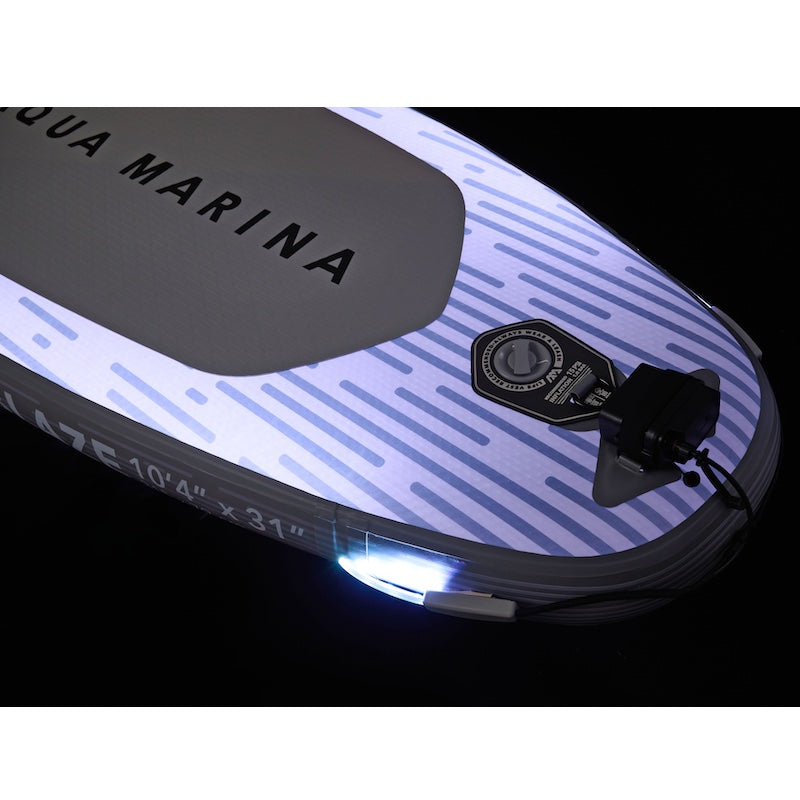 Close-up of an Aqua Marina inflatable stand-up paddleboard with LED lights on a black background.