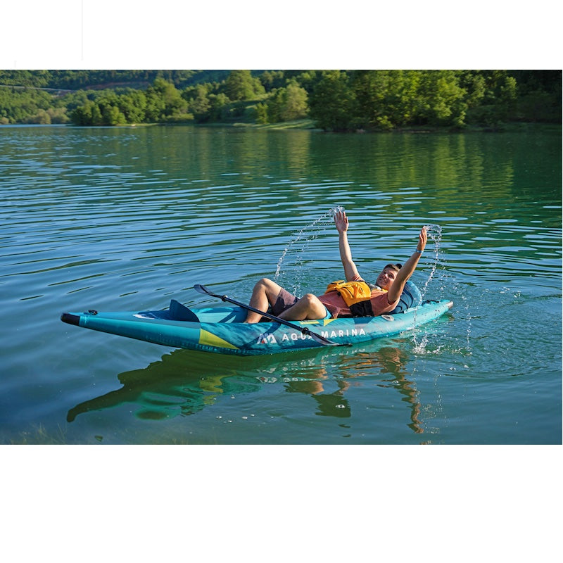 1 man relaxing in a aqua/teel kayak on a calm lake with trees in the background