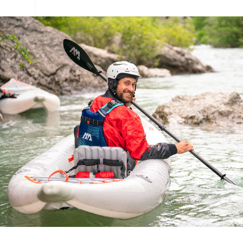 Man paddling a kayak on a river with rocky surroundings