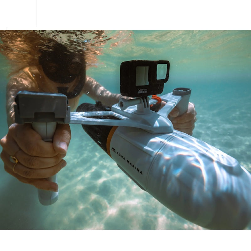 Person with an underwater scooter holding a camera with a housing device, wearing sunglasses.