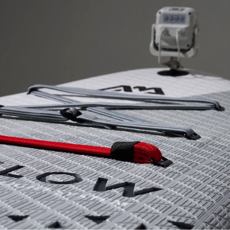 Close-up of a paddleboard with ropes and a camera mounted on a gray background