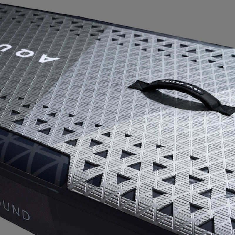 Black and white patterned deck ofan inflatable paddle board with a handle on a gray background