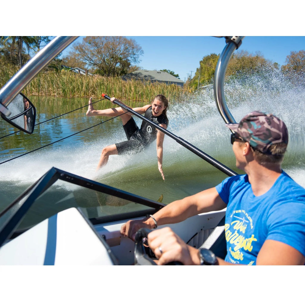 Girl barefoot skis on the side pylon in her Iron sleeveless wetsuit. The view shows the boat driver and skier.