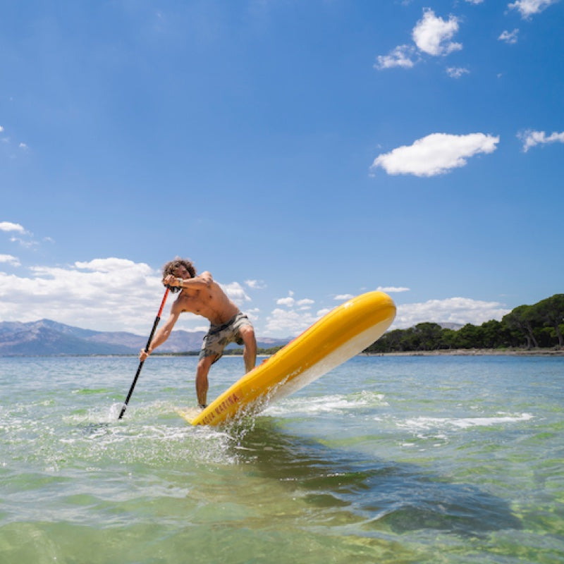 Person paddleboarding on a clear day with mountains in the background