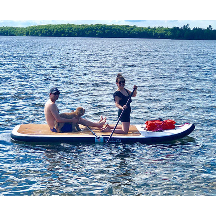 Multi-person inflatable Paddleboard with 2 people paddleboarding with their dog and life vests folded neatly on the side.