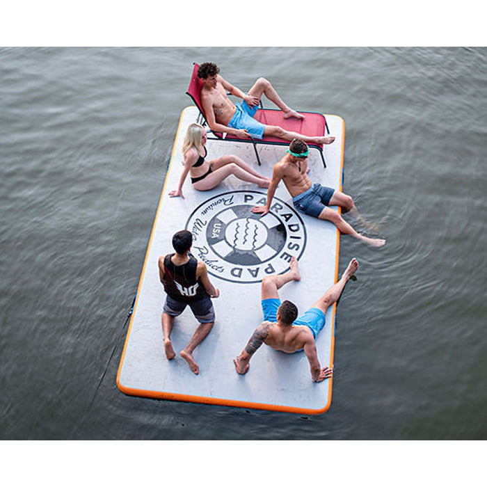 Paradise Pad 6&#39;x13&#39; Inflatable Water Mat with a group of 5 people hanging out on top, one of them resting on a sunbathing chair.