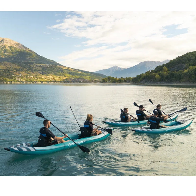 Group of people kayaking on a lake with mountains in the background
