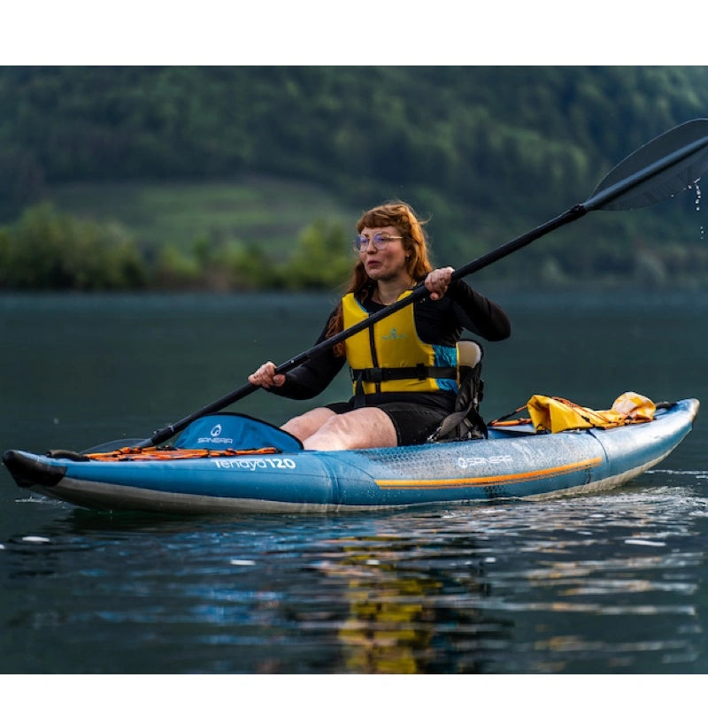 Person kayaking on a lake with a scenic background