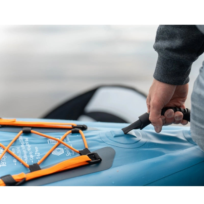 Person carrying an inflatable kayak with a handle. Orange bungee storage right next to it.
