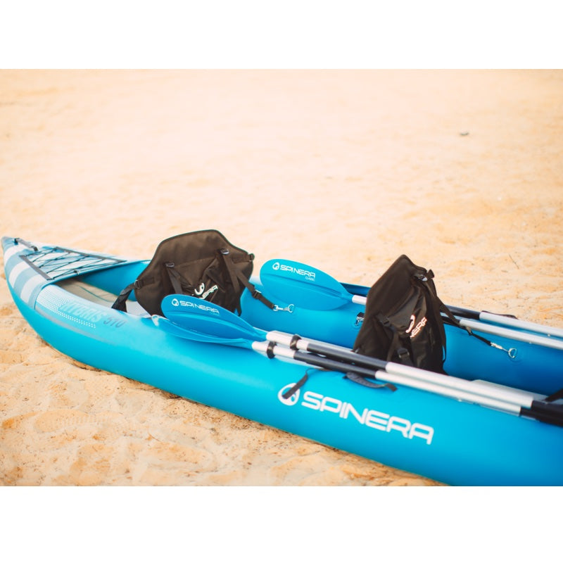 Blue kayak with paddles and bags on a beige surface