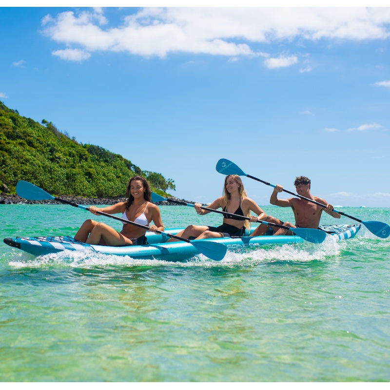 Three people kayaking in clear blue water with a scenic background