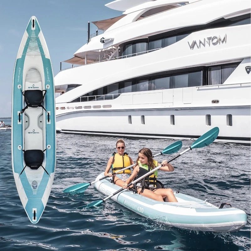 Mom and daughter kayaking in front of a large yacht.