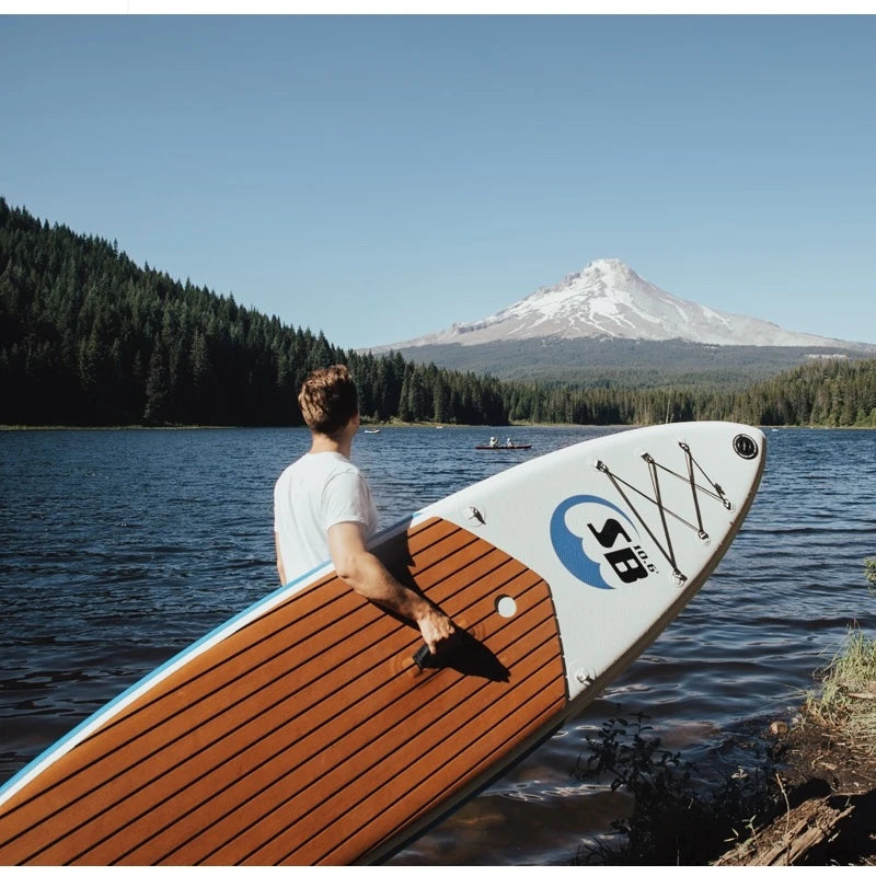Person holding a paddleboard with Mount Hood in the background