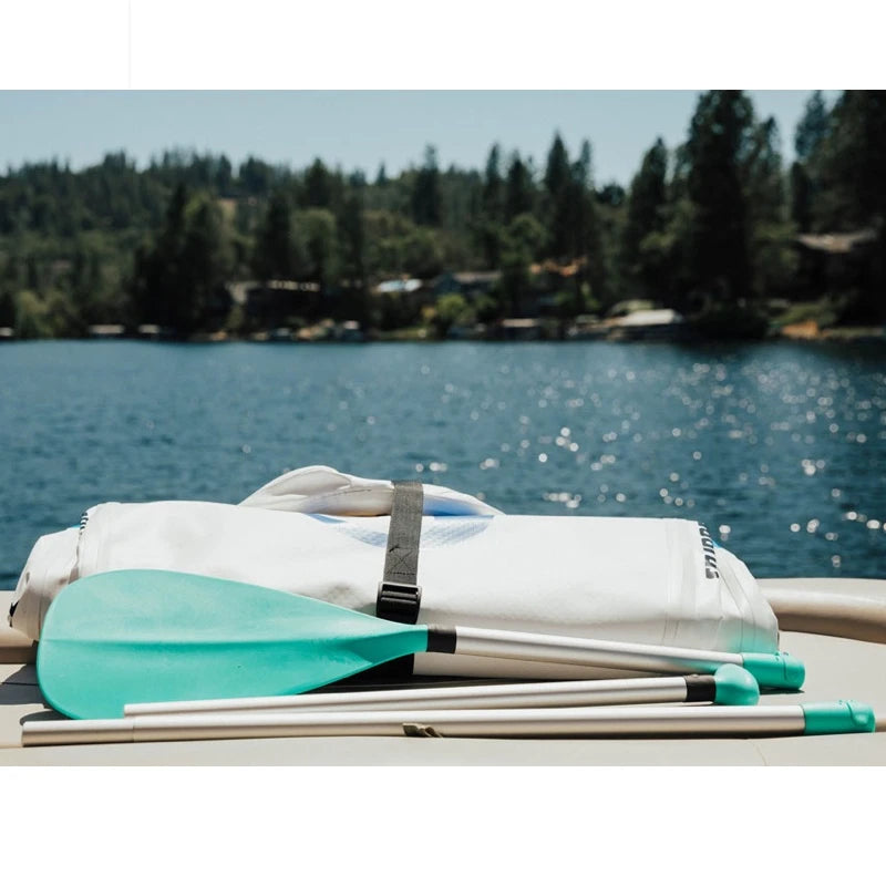 Paddle and folded paddle board on a dock with a lake and trees in the background