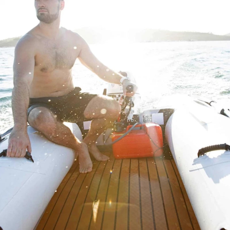 Man motoring an inflatable boat with eva teak deaking. Scenic background.