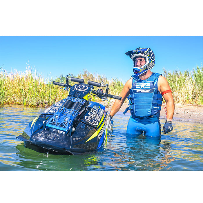 This is the Blue Camo Jetpilot F-86 Sabre John Wetsuit worn by a person while standing beside a jetski on the water.