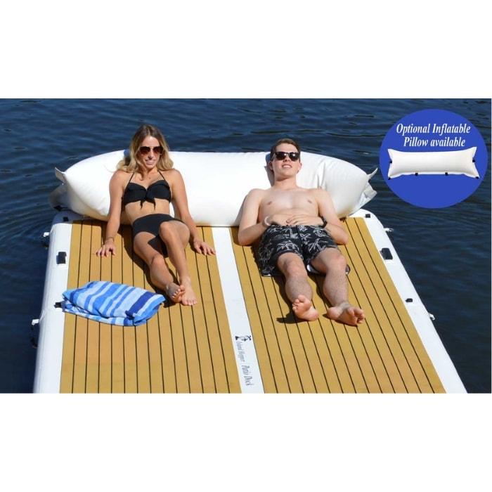 Island Hopper Patio Dock Floating Swim Platform is great for sun tanning. A young boy and young woman are laying on the inflatable floating dock with a big inflatable pillow. The tan eva foam non-slip surface looks great with the white inflatable dock border and a strip of white down the middle.