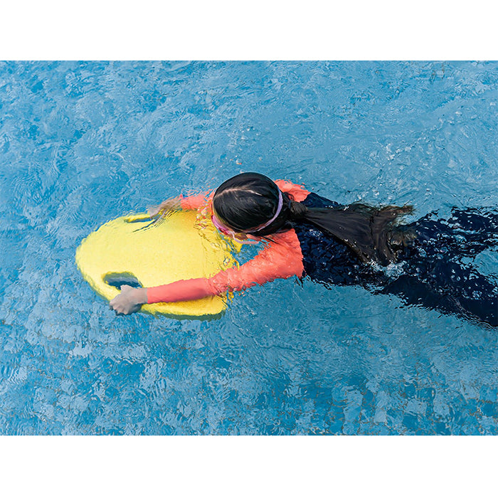 This is the yellow Asiwo Mako Electric Kickboard in being used by a girl in the pool to swim on the water surface.