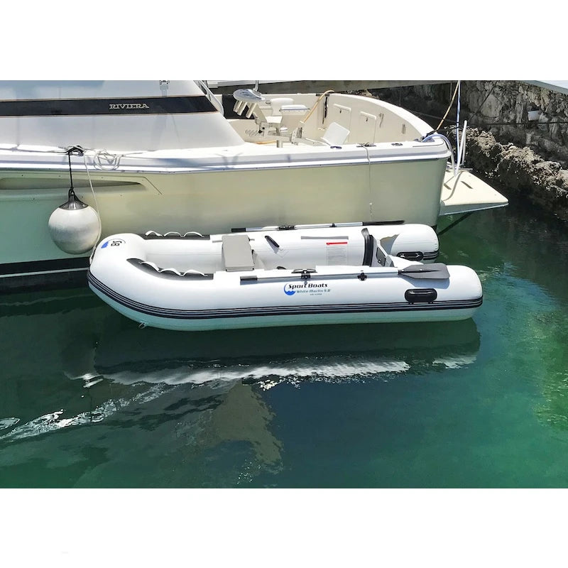 An inflatable boat floating on water is tied to a larger boat in the background.