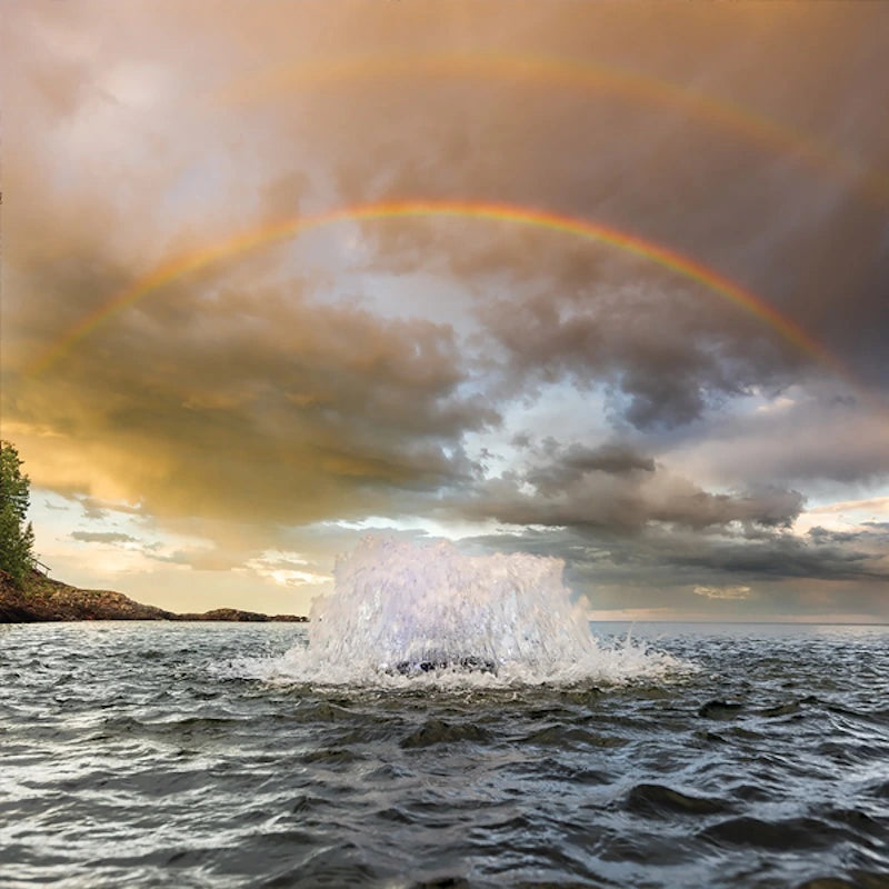 Double rainbow over a lake with water coming up out of the lake from a surface aerator.