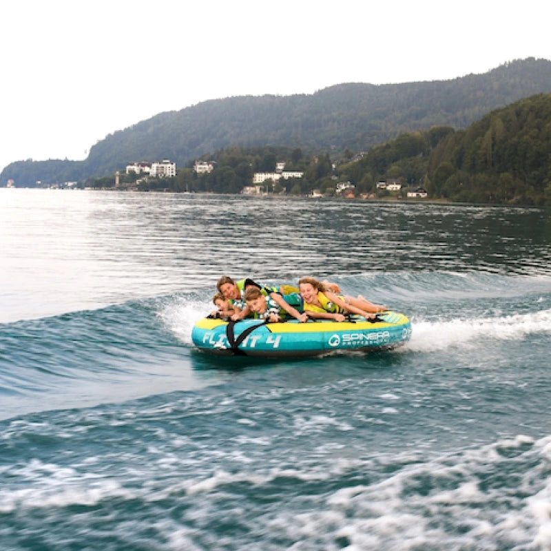 People on a towable tube in a lake with mountains in the background