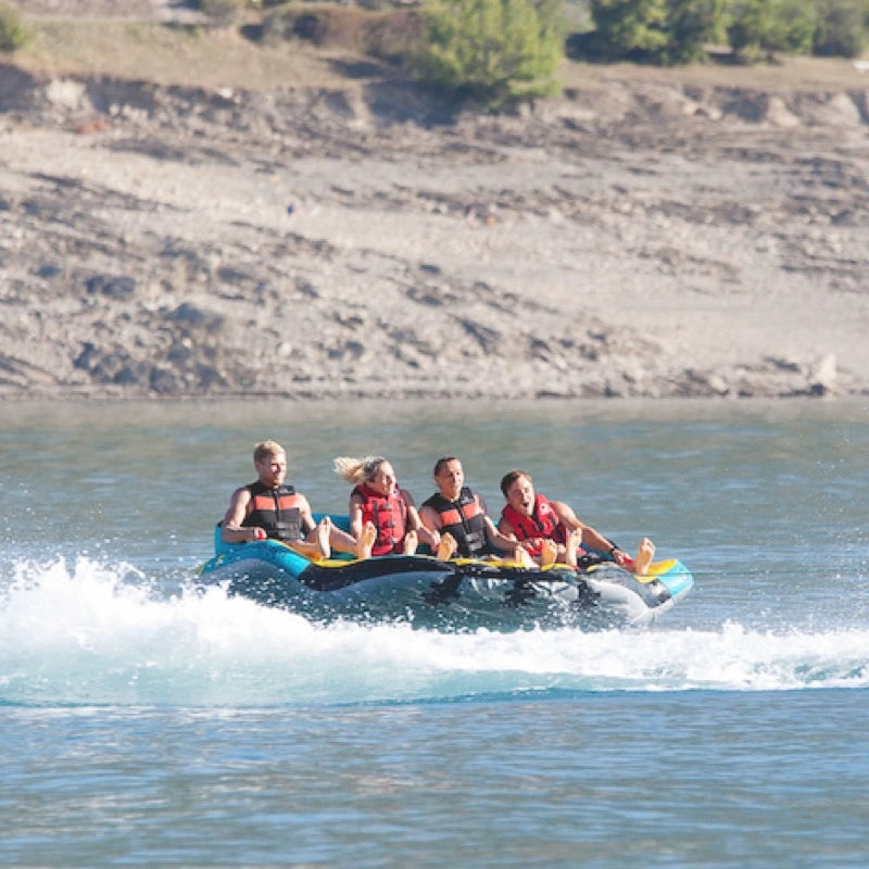 Four people on a tube in the water with a scenic background
