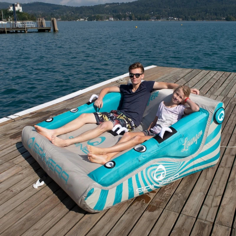 Two people on a large inflatable lounge by a lake