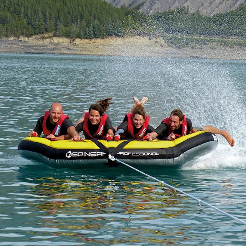 Four people on a Spinera boat tube in a lake with mountains in the background