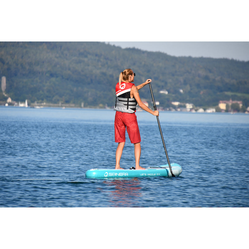 Woman paddleboarding on a lake with mountains in the background