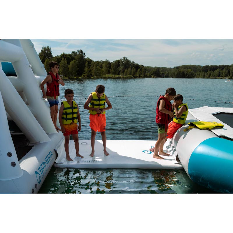Children on an inflatable platform by a lake with trees in the background