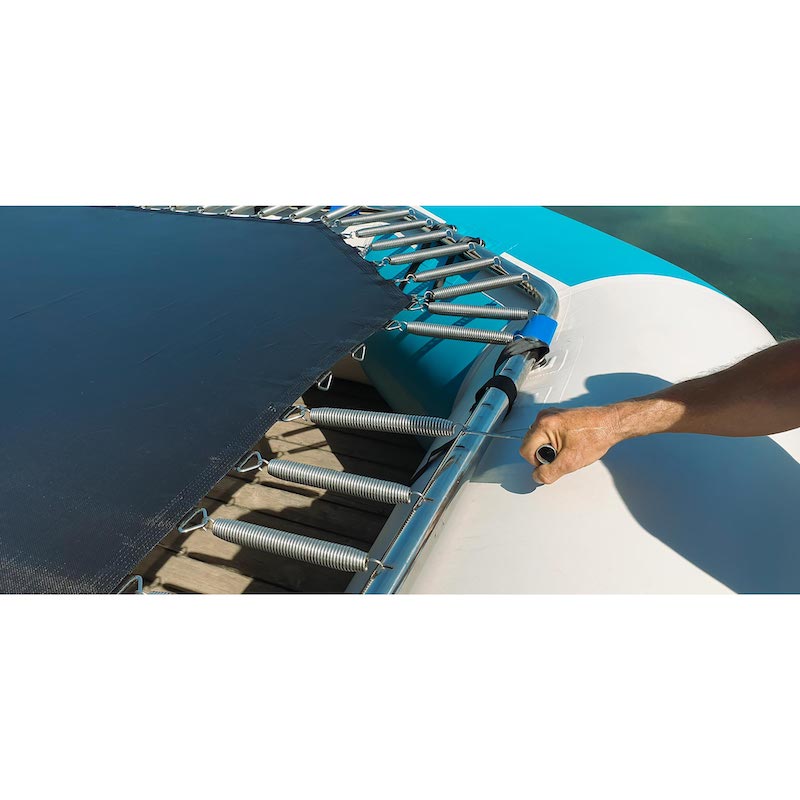 Installing springs on a water trampoline with a tool.