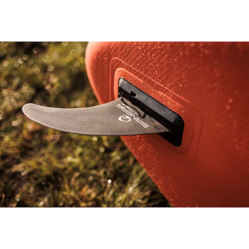 Close-up of a the center fin for the Spinera Supventure paddleboard. On a grassy background.