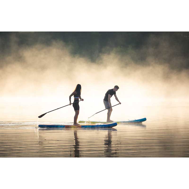Two people paddleboarding on a misty lake