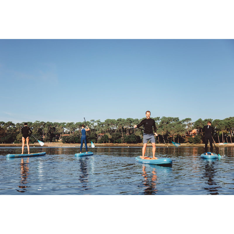 People paddleboarding on a calm body of water with a clear blue sky.