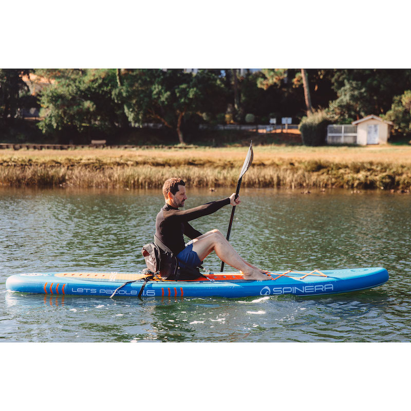Person paddleboarding on a lake with trees and grass in the background