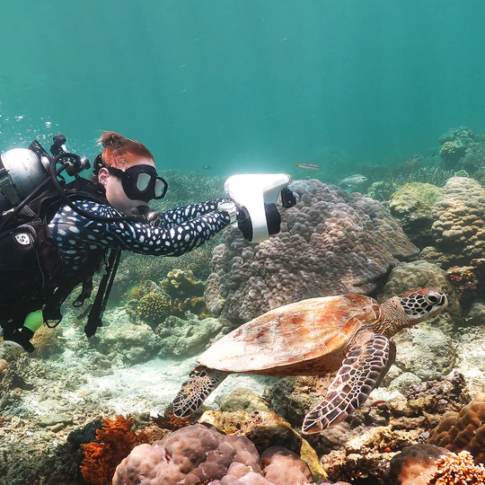 HyperGoGo Manta Sea Scooter in action used by a diver to follow a sea turtle underwater.