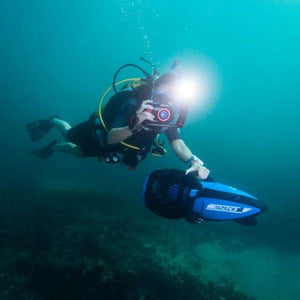 Yamaha 220Li Sea Scooter in use by a scuba diver with 1 hand taking a picture and 1 hand on the Yamaha 220Li Sea Scooter handle.