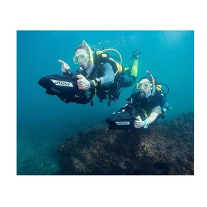 A man and woman are shown navigating their Yamaha 500Li Sea Scooter through the water and over over a reef.  Both people are using their own all black with lime highlights Yamaha 500Li Sea Scooter.