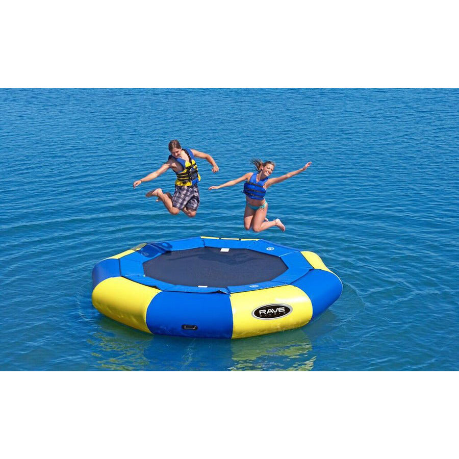 2 girls jumping on the Rave Aqua Jump 120 Eclipse Water Trampoline on the lake.  Panels alternate between yellow and blue around the water trampoline.  Thin blue pad inner ring over the connection to the black water trampoline surface.  Black Rave logo on one of the yellow panels. 