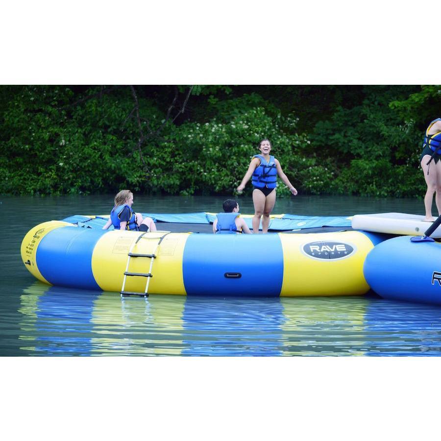 Adults and kids playing on the yellow and blue Rave Aqua Jump Eclipse 200 Water Trampoline out on the lake.  Ladder is visible on the side. 