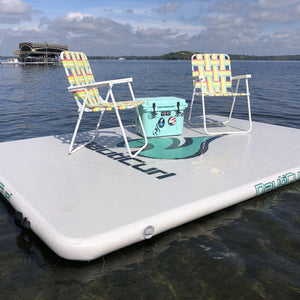 NautiPad Inflatable Swim Mat on the water with 2 beach chairs and an ice-box in the middle on it.
